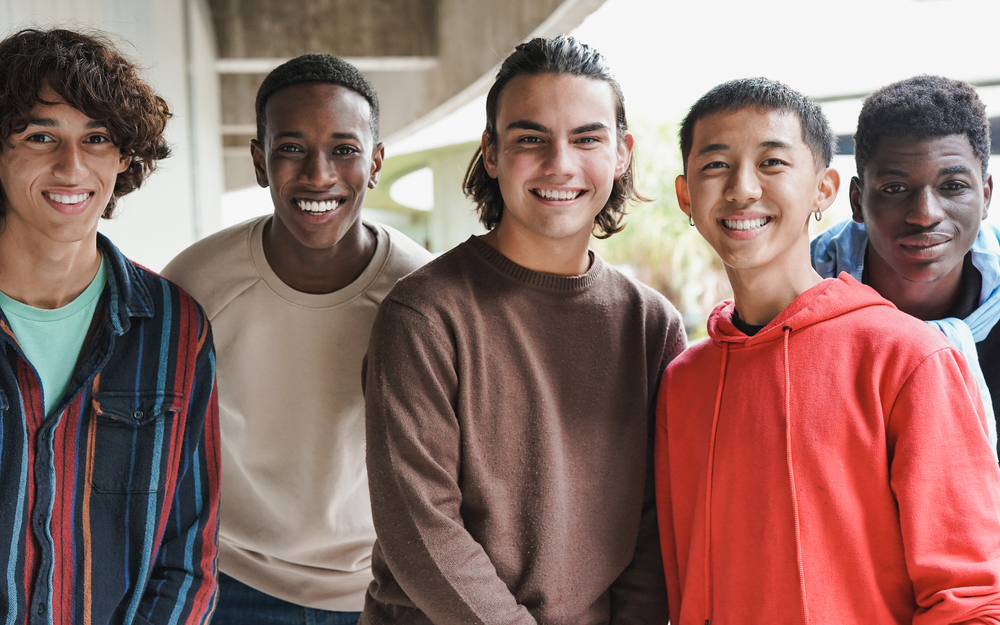 group of happy multiethnic boys smiling on camera at school outd