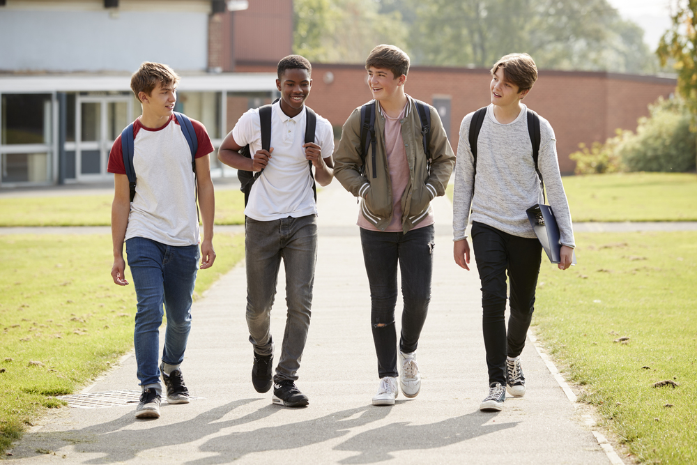 group of male teenage students walking around college campus