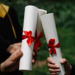 Three diplomas with red ribbons symbolize graduation success outdoors.